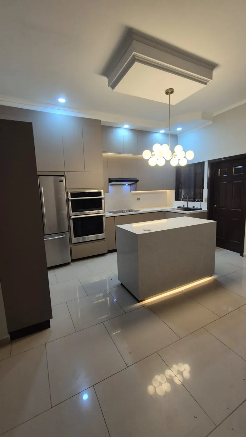 Cocina gris con isla iluminada, hecha por Mundo Muebles y Más